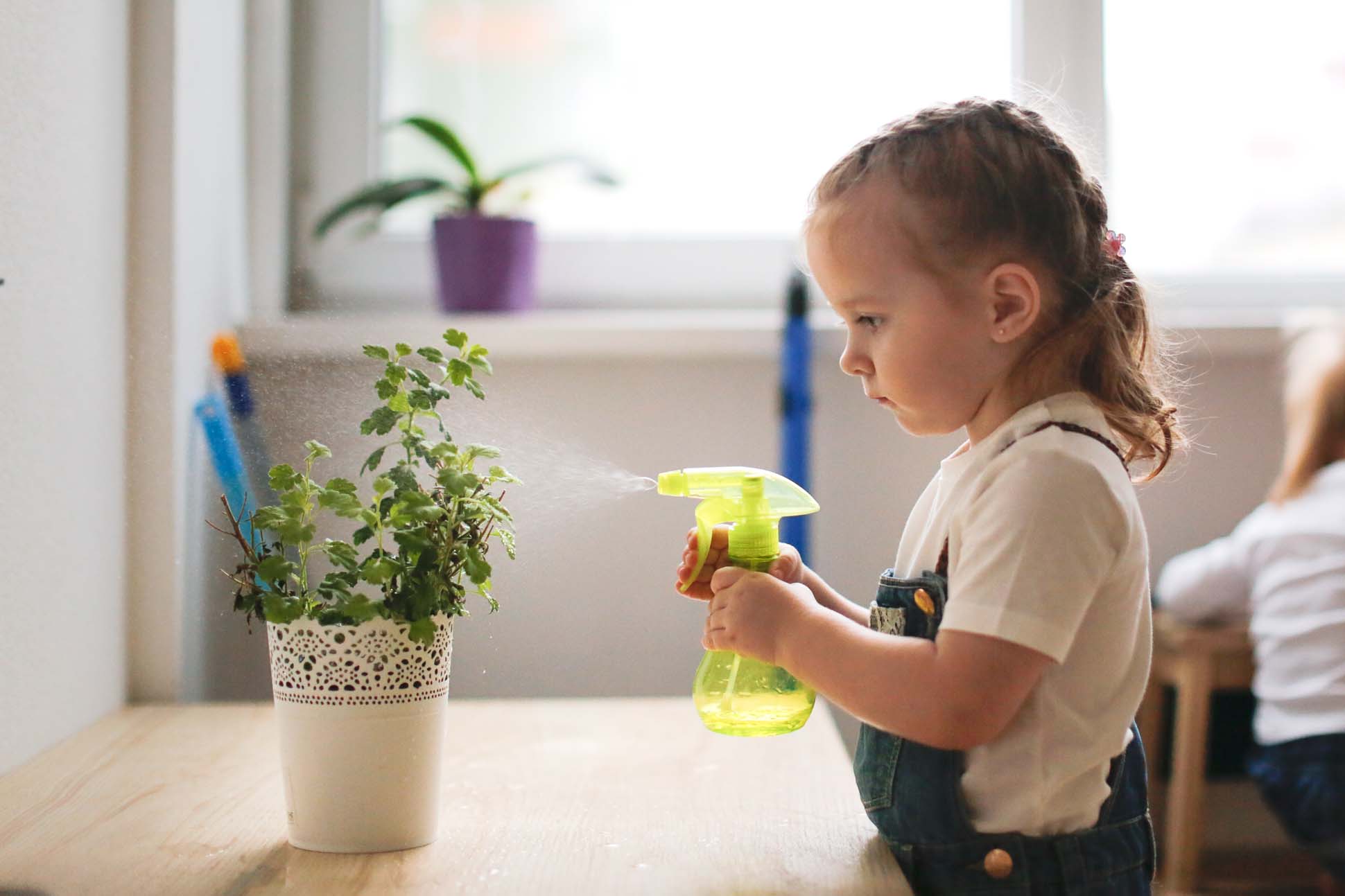 Toddler with brown hair watering a house plant, Moorside Pre-School - Nursery Education Lancaster